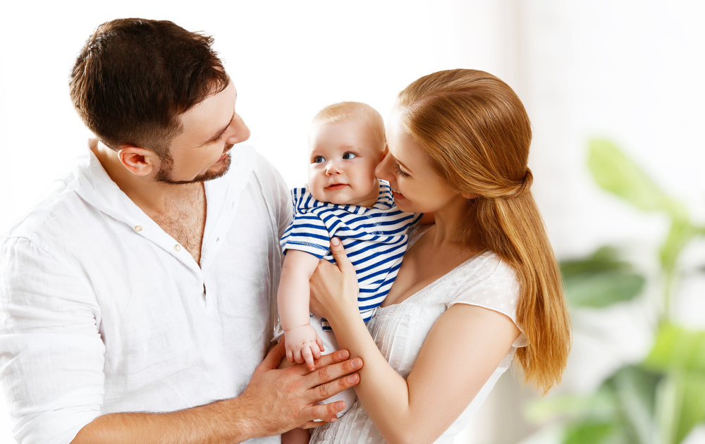 Anne ve baba bebeğiyle birlikte gülümserken